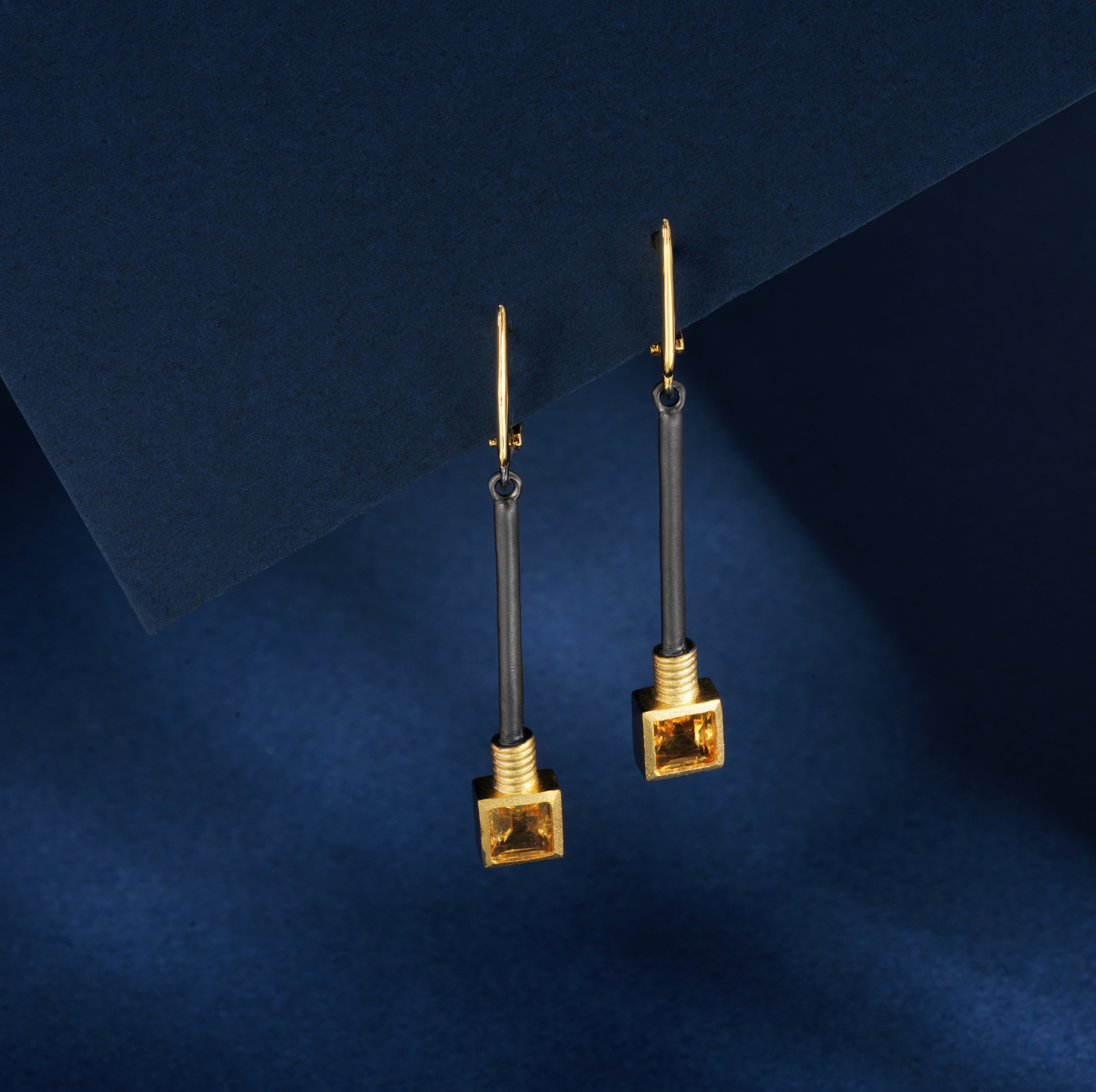 A pair of silver earrings with gold, black rhodium and yellow citrine stones.