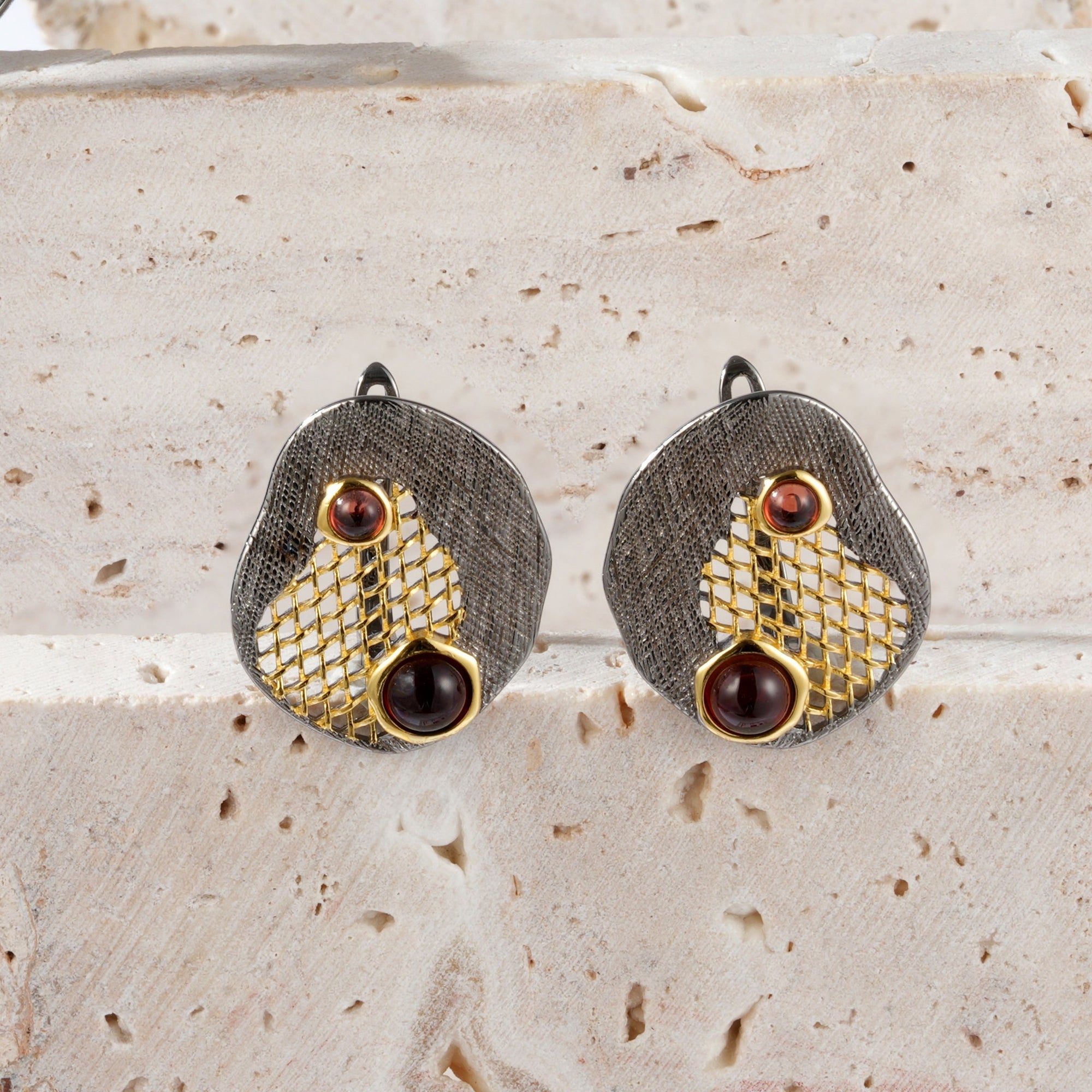A pair of silver gold plated earrings with red garnet stones and black rhodium.