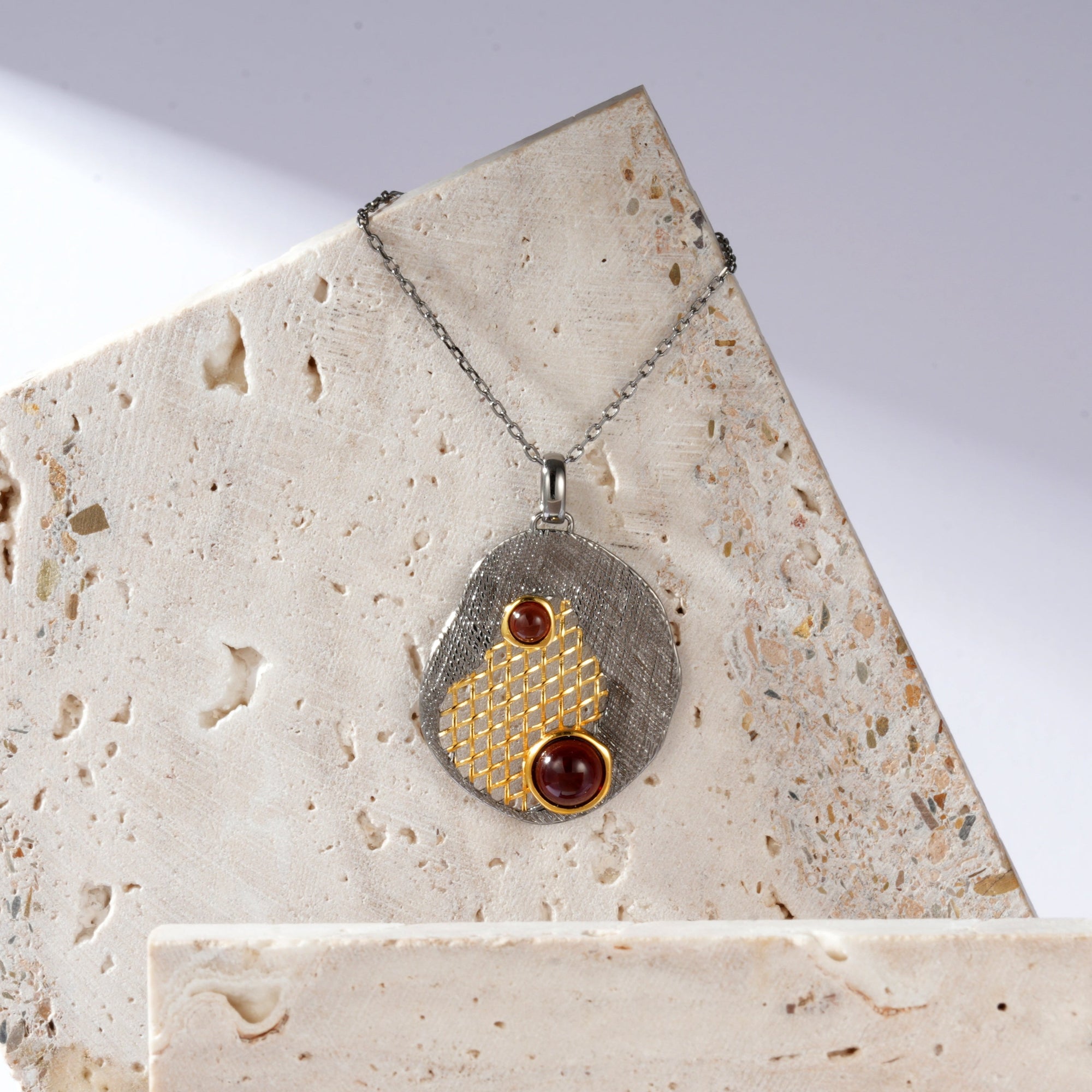 A silver gold plated necklace with red garnet stones and black rhodium.